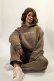 Oracle Hoodie in Desert Clay — Female Model Sitting